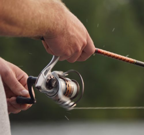 focus photo of man holding fishing rod and fishing reel