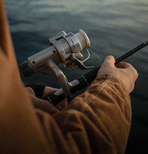 person in brown pants and black and gray fishing rod